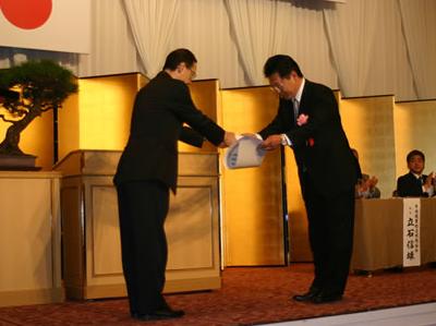 表彰式の様子。表彰状と銀杯を受け取る代表取締役の中内晃次郎氏(写真右)