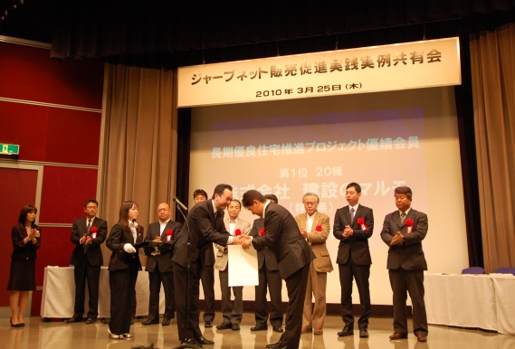 「長期優良住宅普及促進事業」の補助金交付件数20件でネットワークトップとなった(株)建設のマルモ代表取締役社長:望月博司氏(右)を表彰する、ジャーブネット主宰:宮沢俊哉氏