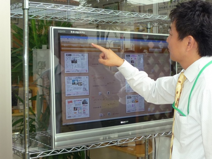 屋外での店頭電子看板(デジタルサイネージ)としての使用例。窓越しから画面に触れることで情報を取得できる