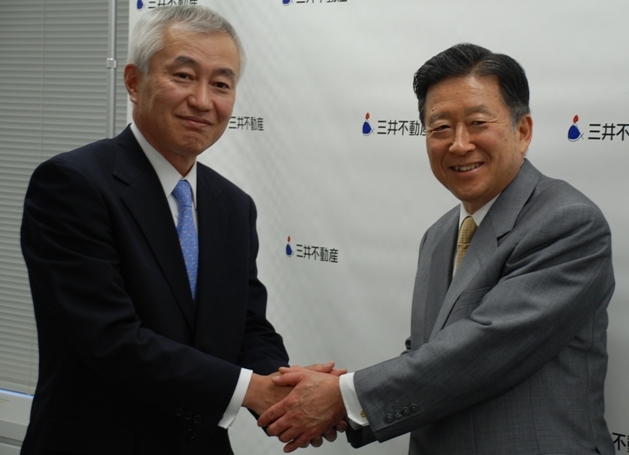 社長交代会見後に握手を交わす岩沙弘道社長(右)と、菰田正信次期社長(左)