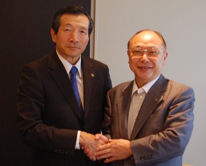 新理事長に就任する袖山靖雄氏(左)と握手を交わす池田行雄理事長