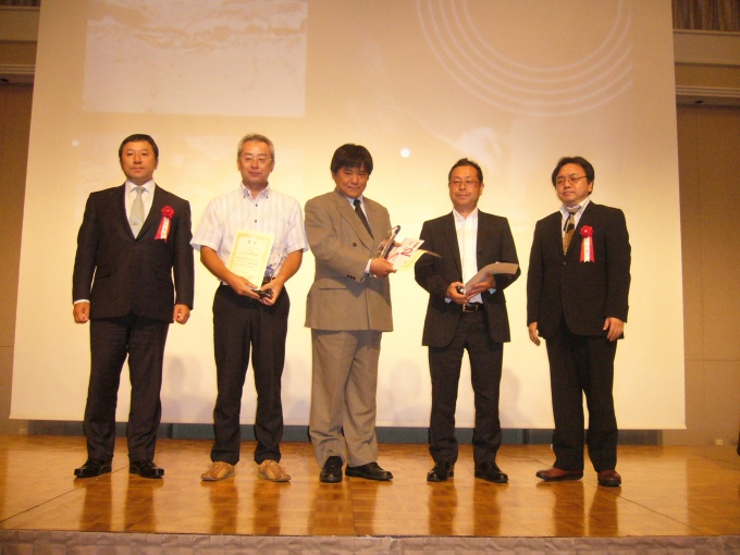 受注キャンペーン表彰式の様子。同社代表取締役社長の濵村聖一氏(右)と、ハイスピードコーポレーション(株)代表取締役・松下博行氏(左)に祝福される、受賞者3名