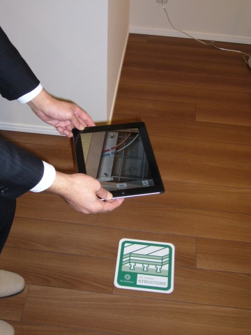 iPadでモデルルーム内の床に設置したARマーカーを映している様子。画面上にはCGで床下の構造が現れた