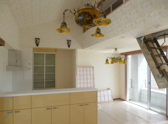 オレンジ色を基調にしたキッチン。壁紙や照明にもこだわりのデザインを採用。リビングの天井には、物置用のロフトが設けられている