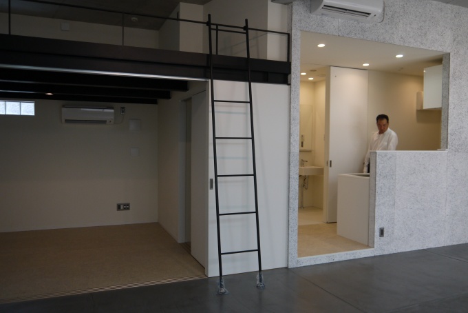1階の1LDK+ロフトの住戸。天井高が高いためロフト内もゆとりがある。土間加工してあるリビング・ダイニング(写真手前部分)をオフィススペース、ロフト内をプライベートスペースとして、ゾーニングしながら利用することも可能
