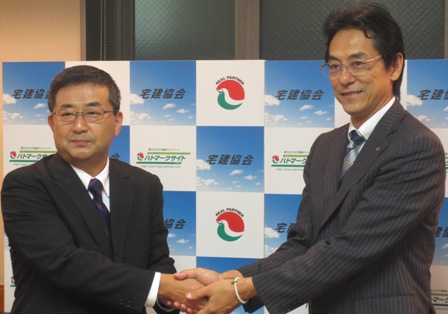 提携に向け握手を交わす、ハトマーク支援機構・和氣猛仁理事長(写真右)とジャックス・根本雅行執行役員(写真左)