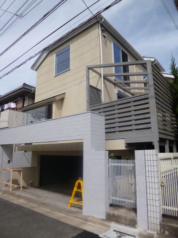 「世田谷野毛の家」外観は吹付塗装で仕上げた。1階部分には木材でテラスを造りつけ、2階部分のベランダはなくすことで採光性を高めた
