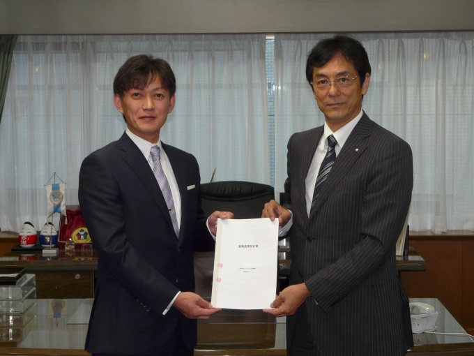 調印書を交換するハトマーク支援機構理事長の和氣猛仁氏(右)と、Casa代表取締役社長の宮地正剛氏(左)