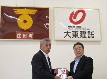 寄付金受領式で、(右)同社取締役執行役員・齊藤和彦氏より(左)住田町長・多田欣一氏へ寄付金を渡している様子