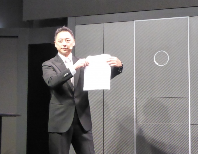 試作品の全自動洗濯物折り畳み機(写真右)で畳んだTシャツをアピールするセブンドリーマーズの阪根社長