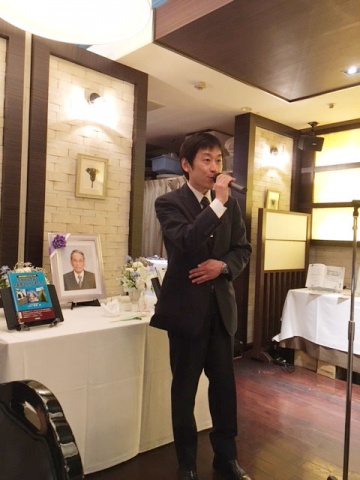 吉野 伸氏の遺影の前で、「縁を大切にしながら、これからも不動産業界の役に立てるよう尽力していきたい」と述べる吉野荘平氏