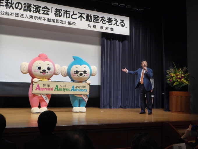 講演会では公式キャラクターの着ぐるみを披露した(写真左)。「公式キャラクターによる不動産鑑定士業のPRを加速する」していく話す吉村会長(写真右)